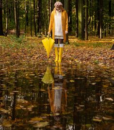 a woman in yellow rain boots is walking through the woods with her umbrella and water