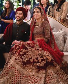 a man and woman sitting on top of a couch next to each other in wedding outfits