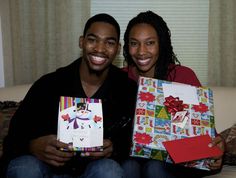 a man and woman sitting on a couch holding gift boxes in their hands, both smiling at the camera