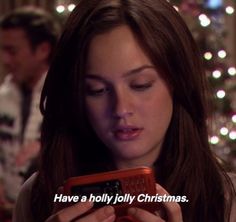 a woman looking at her cell phone with the words have a holly holly christmas on it