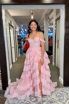 a woman standing in front of a mirror wearing a pink dress with high slits