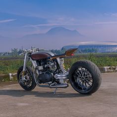 a motorcycle parked on the side of a road with mountains in the backgroud