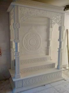 a white bed sitting in the middle of a room next to a wall with an intricate design on it