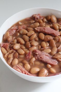 a white bowl filled with beans and ham