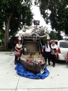 three people dressed up in pirate costumes standing next to a car with an open trunk