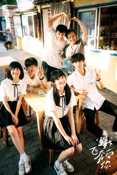 a group of young people sitting around a wooden table