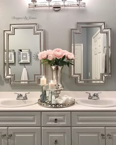 a bathroom with two sinks, mirrors and flowers in the vase on the sink counter