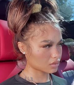 a woman with piercings on her nose sitting in a car