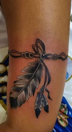 a woman's leg with a tattoo on it that has an arrow and feathers attached to it