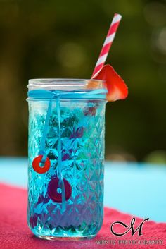 a glass jar with a straw and some liquid in it sitting on a red table cloth