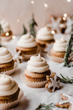 cupcakes with white frosting and cinnamon stars on top, surrounded by christmas decorations