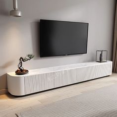 a flat screen tv mounted to the side of a wall next to a white cabinet