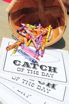 a bucket full of crayons sitting on top of a table next to a sign that says catch of the day