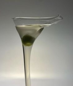 a wine glass filled with white liquid and an olive