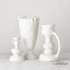 three white vases sitting next to each other on a table