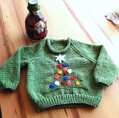 a green sweater sitting on top of a wooden table next to a jar of candy