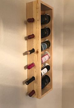 a wooden wine rack with six bottles in it and two on the wall behind it