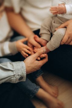 a group of people holding hands together in the middle of their fingers, with one baby being held by two adults