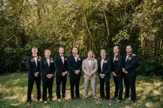 a group of men standing next to each other in front of trees