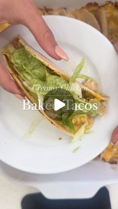 a person holding a plate with a taco on it that has guacamole and lettuce in it