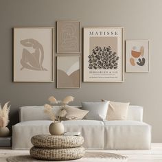 a living room filled with white furniture and pictures on the wall above it's coffee table