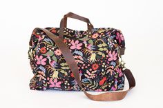 a black and pink floral bag with brown straps