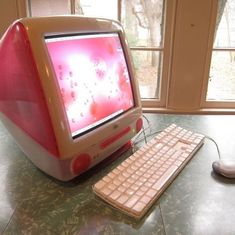 an old computer sitting on top of a table next to a keyboard and mouse with windows in the background