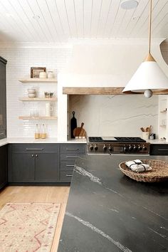 a kitchen with black counter tops and white walls, along with an area rug on the floor