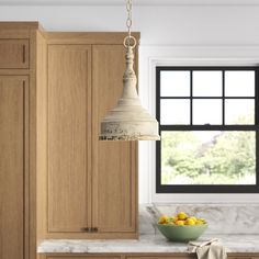 a kitchen with wooden cabinets and white marble counter tops, hanging light fixture over the island