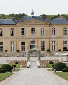 an outdoor wedding venue in front of a large building with lots of greenery on the lawn