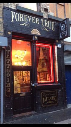 the storefront of a tattoo parlor with neon lights in it's window display