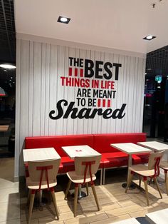 the interior of a restaurant with red booths and white tables, along with a large sign on the wall that says the best things in life are meant to be shared