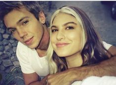 a man and woman are smiling for the camera while laying down on the ground with their arms around each other