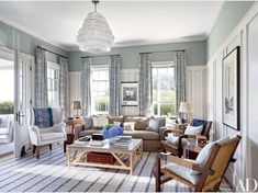 a living room filled with lots of furniture and windows covered in blue draping