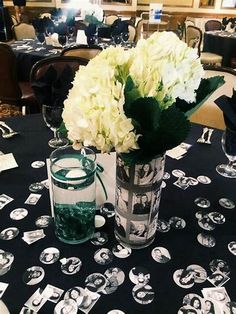 a vase with white flowers sitting on top of a table next to two empty glasses