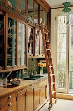 a ladder leaning up against a window in a kitchen next to a sink and cabinets