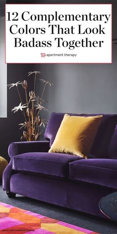 a purple couch sitting on top of a rug next to a vase with flowers in it