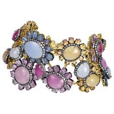 Introducing our breathtaking Victorian 110 Cttw. Sapphire, Ruby, and Diamond Link Bracelet, a true masterpiece of elegance and sophistication. This stunning bracelet features a captivating collection of floral motifs adorned with vibrant sapphires in shades of blue, pink, and yellow. Each floral motif showcases a round or oval sapphire at its core, encircled by a halo of shimmering diamonds set on a backdrop of black rhodium. These motifs are intricately linked together with oval rubies, creatin Multicolor Multi-stone Luxury Diamond Bracelet, Luxury Multi-stone Diamond Bracelet, Luxury Multi-stone Diamond Bracelet For Formal Occasions, Luxury Multicolor Diamond Bracelet For Formal Occasions, Multicolor Luxury Diamond Bracelet For Formal Occasions, Multicolor Diamond Bracelet For Formal Occasions, Luxury Multicolor Diamond Bracelets, Elegant Multicolor Diamond Bracelet For Formal Occasions, Elegant Multi-stone Diamond Bracelet