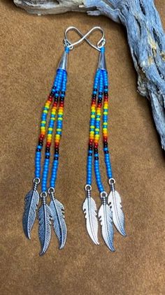 two pairs of earrings with feathers hanging from them