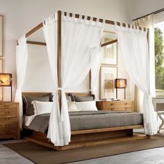 a bedroom with four poster bed and white drapes