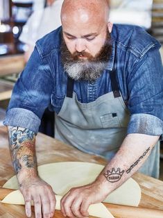 a man making pizza dough on top of a wooden table