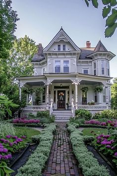 a large white house with lots of flowers in the front yard