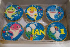 six decorated cupcakes in a box with the name jan on them and various types of sharks