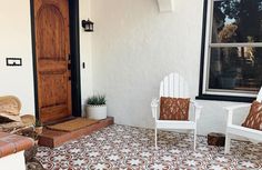 two white chairs sitting on top of a tiled floor next to a wooden door and window