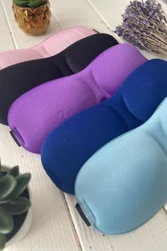 three different colored pillows sitting on top of a table next to a potted plant