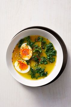 a white bowl filled with soup and an egg