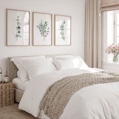 a bed with white sheets and pillows in a bedroom next to two pictures on the wall