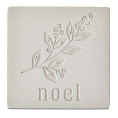 a white tile with the word noel written on it and an image of a plant