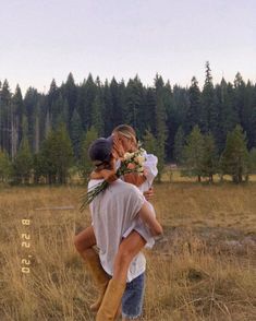 two people are hugging in the middle of a field