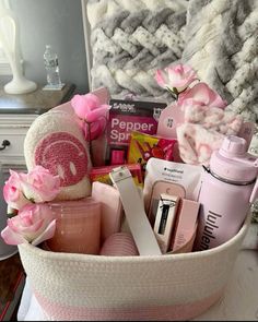 a white basket filled with lots of pink items on top of a table next to a bed